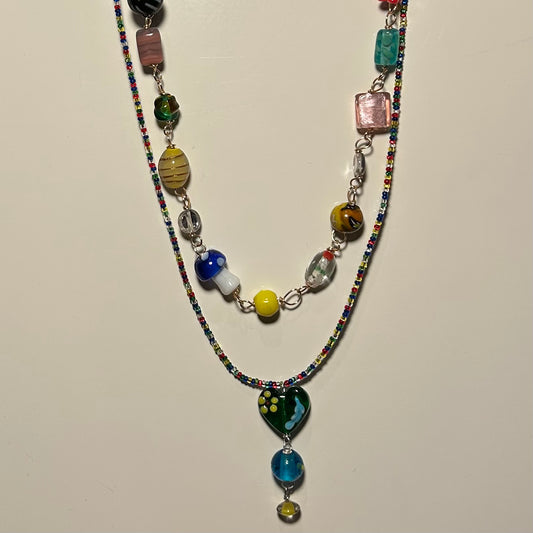 Two brightly beaded necklaces shown hanging. 